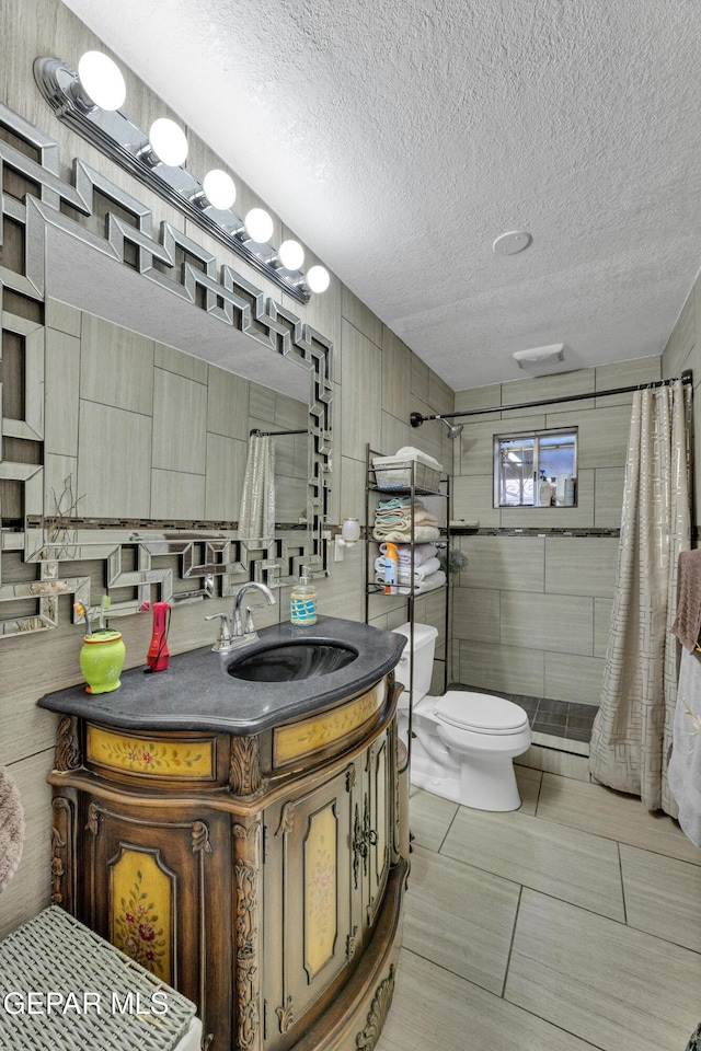 11749 Socorro Rd, Socorro, TX 79927 - full bath with tiled shower, vanity, a textured ceiling, tile walls, and tile patterned floors