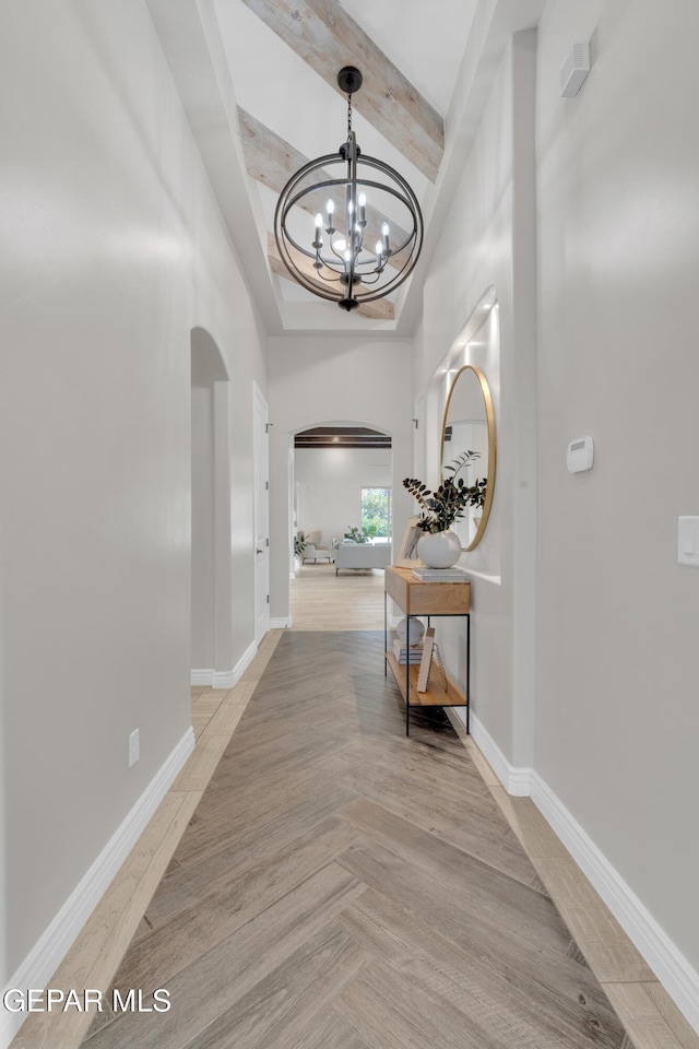 7424 Cimarron Gap Dr, El Paso, TX 79911 - hallway featuring arched walkways, a chandelier, beam ceiling, a towering ceiling, and light wood-style floors