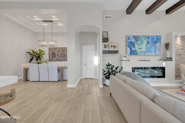 7424 Cimarron Gap Dr, El Paso, TX 79911 - living room with arched walkways, wood finished floors, a chandelier, a tray ceiling, and beamed ceiling