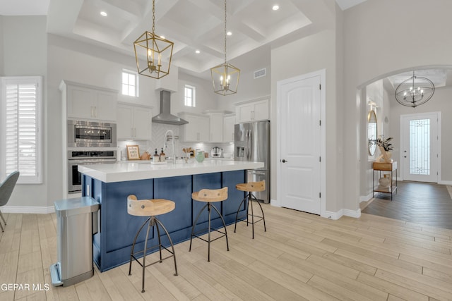7424 Cimarron Gap Dr, El Paso, TX 79911 - kitchen with appliances with stainless steel finishes, a chandelier, a towering ceiling, wall chimney range hood, and coffered ceiling