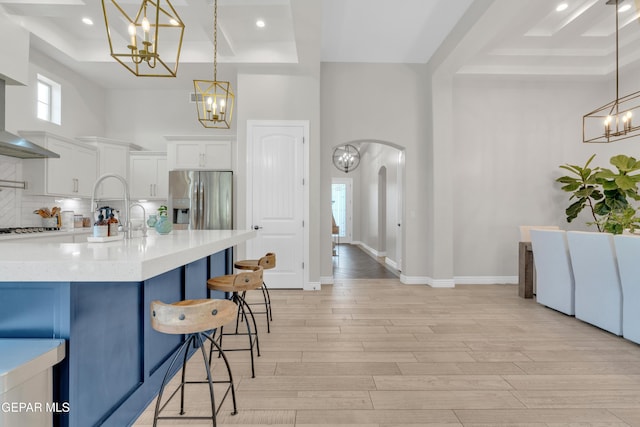 7424 Cimarron Gap Dr, El Paso, TX 79911 - kitchen featuring a chandelier, a kitchen breakfast bar, light wood finished floors, white cabinetry, and a towering ceiling