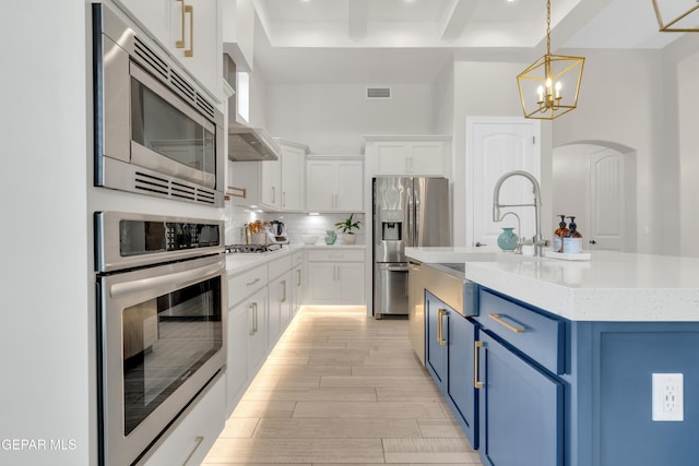 7424 Cimarron Gap Dr, El Paso, TX 79911 - kitchen featuring stainless steel appliances, blue cabinetry, arched walkways, white cabinetry, and light wood-style floors