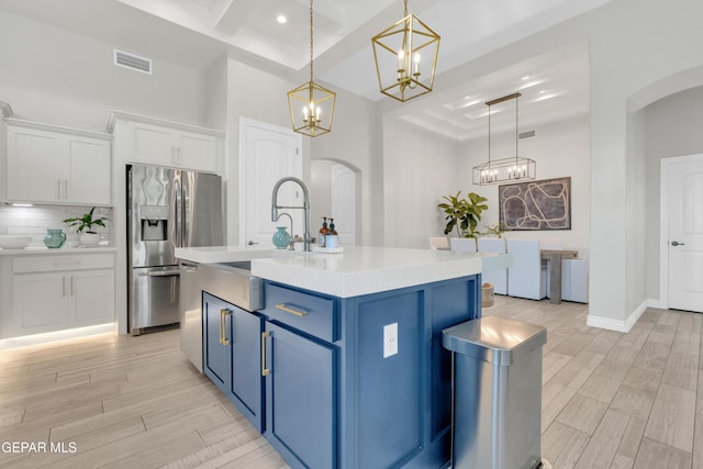 7424 Cimarron Gap Dr, El Paso, TX 79911 - kitchen featuring arched walkways, blue cabinets, appliances with stainless steel finishes, a chandelier, and white cabinetry