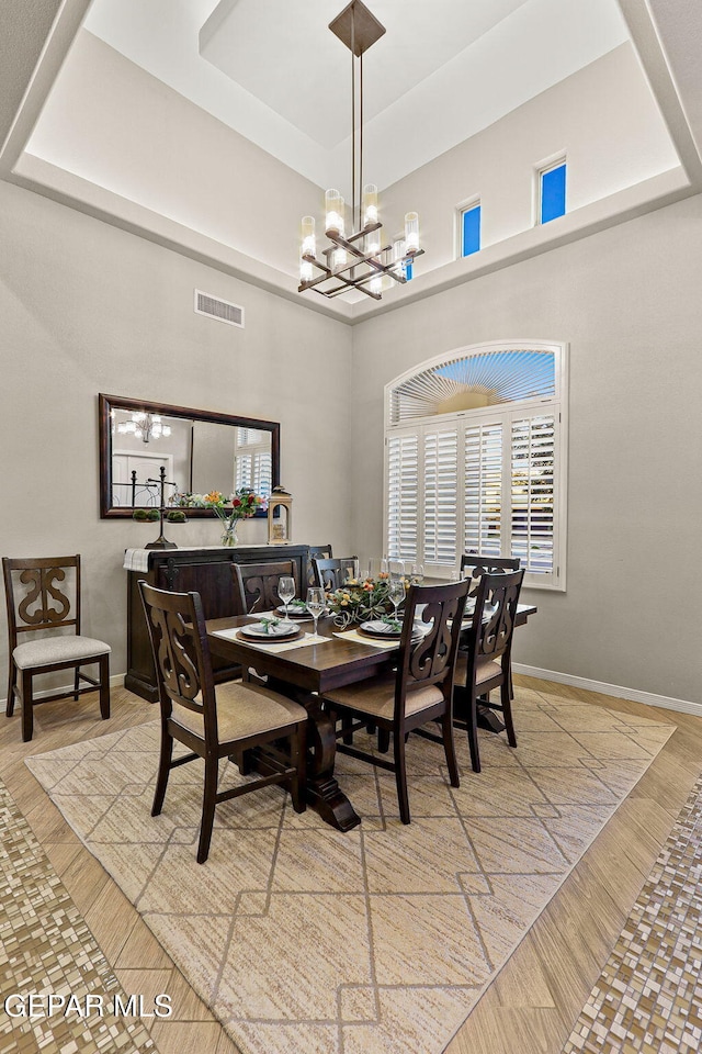 12289 Freshwater Dr, El Paso, TX 79928 - dining room with a chandelier, a raised ceiling, light wood-style flooring, and a high ceiling