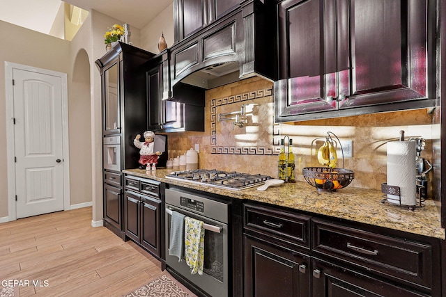 12289 Freshwater Dr, El Paso, TX 79928 - kitchen featuring stainless steel appliances, arched walkways, light stone counters, and tasteful backsplash