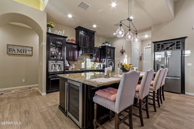 12289 Freshwater Dr, El Paso, TX 79928 - kitchen with stainless steel appliances, wine cooler, light wood-type flooring, dark cabinets, and recessed lighting