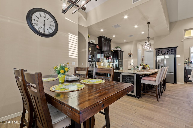 12289 Freshwater Dr, El Paso, TX 79928 - dining space featuring wine cooler, a chandelier, light wood-type flooring, recessed lighting, and a towering ceiling