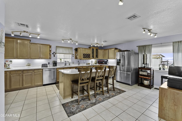 34 Kingery Dr, El Paso, TX 79902 - kitchen with stainless steel appliances, track lighting, light countertops, light tile patterned flooring, and a kitchen island