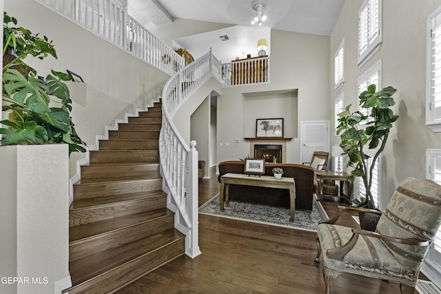 34 Kingery Dr, El Paso, TX 79902 - staircase featuring high vaulted ceiling, a warm lit fireplace, and wood finished floors