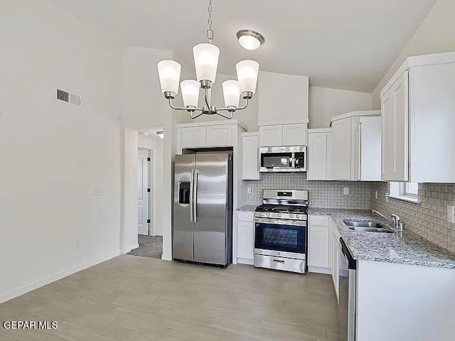 14309 Seth Payne Dr, El Paso, TX 79928 - kitchen with appliances with stainless steel finishes, a chandelier, decorative backsplash, light stone counters, and high vaulted ceiling