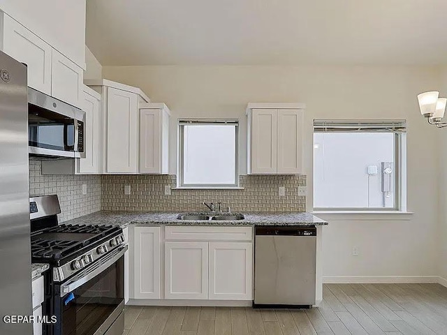 14309 Seth Payne Dr, El Paso, TX 79928 - kitchen with stainless steel appliances, decorative backsplash, light stone countertops, white cabinetry, and light wood-style floors