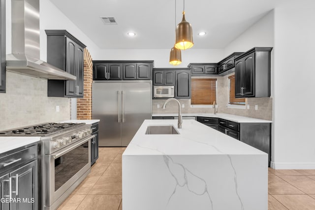 5833 Sundale Rd, El Paso, TX 79912 - kitchen with wall chimney exhaust hood, high quality appliances, light tile patterned floors, light stone countertops, and decorative backsplash