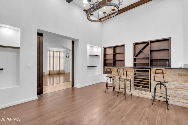 5833 Sundale Rd, El Paso, TX 79912 - dining room featuring beverage cooler, a towering ceiling, built in shelves, wood finished floors, and arched walkways