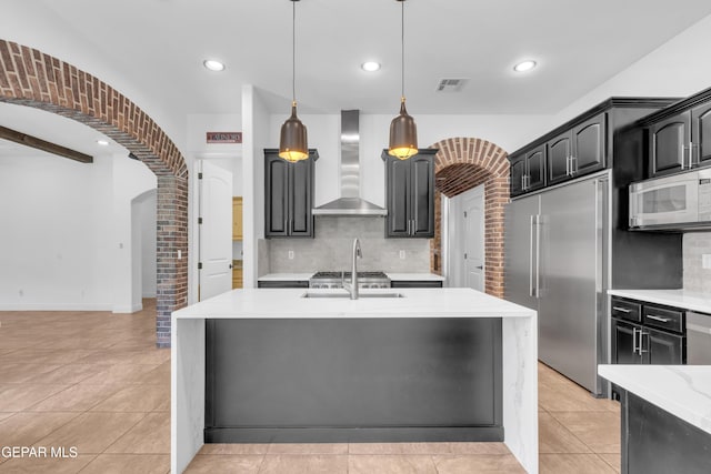 5833 Sundale Rd, El Paso, TX 79912 - kitchen featuring wall chimney exhaust hood, white microwave, stainless steel built in fridge, arched walkways, and decorative backsplash