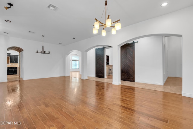 5833 Sundale Rd, El Paso, TX 79912 - unfurnished living room with a chandelier, arched walkways, light wood-style flooring, and recessed lighting
