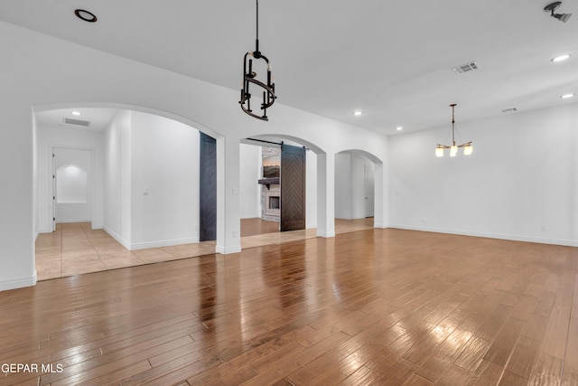 5833 Sundale Rd, El Paso, TX 79912 - unfurnished living room with a chandelier, light wood-style floors, recessed lighting, and arched walkways
