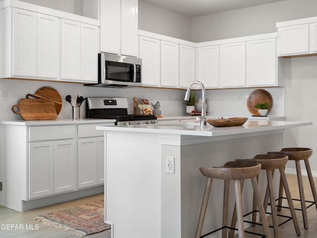 2221 Moon Loft Pl, El Paso, TX 79911 - kitchen featuring appliances with stainless steel finishes, a kitchen breakfast bar, light countertops, tasteful backsplash, and a center island with sink
