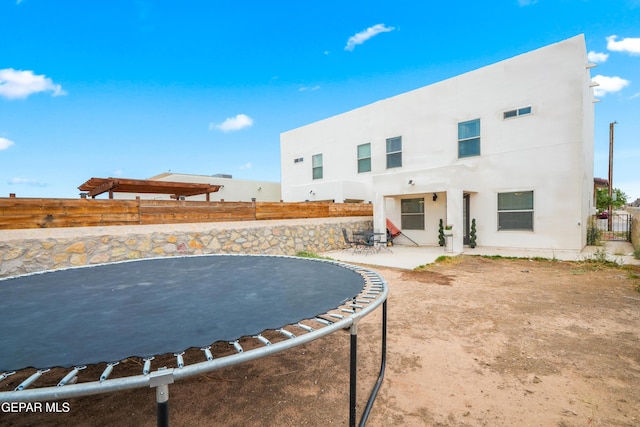 801 Hc Gilbert Minjares Dr Unit A, Socorro, TX 79927 - rear view of house with a trampoline, a fenced backyard, a patio area, and stucco siding