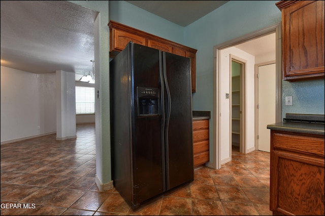 3517 Tierra Bahia Dr, El Paso, TX 79938 - kitchen featuring black fridge, dark countertops, and brown cabinetry
