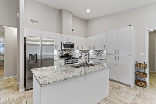 14744 Charles Foster Ave, El Paso, TX 79938 - kitchen with appliances with stainless steel finishes, a towering ceiling, backsplash, a kitchen island with sink, and light stone countertops