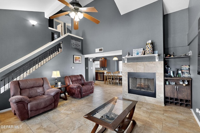 4640 Beacham St, El Paso, TX 79938 - living room featuring stairway, a ceiling fan, a towering ceiling, a tile fireplace, and beam ceiling