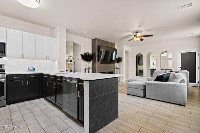 12334 Westbury, El Paso, TX 79928 - kitchen with stainless steel appliances, dark cabinetry, arched walkways, a peninsula, and decorative backsplash