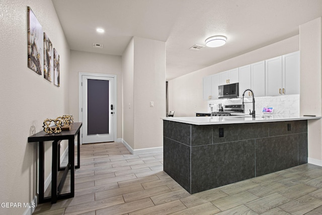 12334 Westbury, El Paso, TX 79928 - kitchen with stove, white cabinets, black microwave, a peninsula, and wood tiled floors