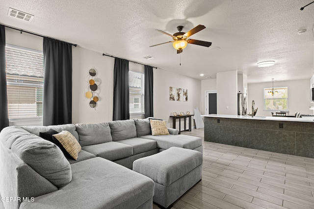 12334 Westbury, El Paso, TX 79928 - living room featuring a textured ceiling, a ceiling fan, and a chandelier