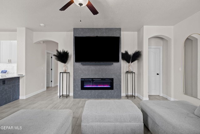 12334 Westbury, El Paso, TX 79928 - living area with ceiling fan, light wood finished floors, arched walkways, and a tiled fireplace