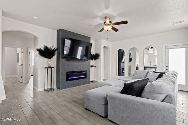 12334 Westbury, El Paso, TX 79928 - living room featuring a ceiling fan, a fireplace, arched walkways, and light wood-style flooring
