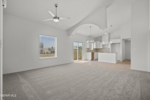 224 Penbridge Pl, El Paso, TX 79928 - unfurnished living room with light carpet, a chandelier, a ceiling fan, vaulted ceiling, and arched walkways