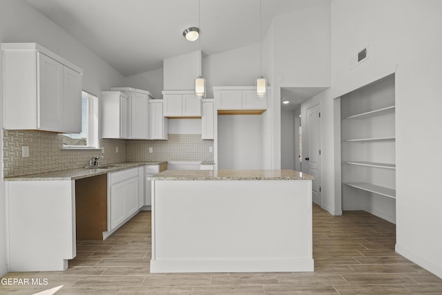 224 Penbridge Pl, El Paso, TX 79928 - kitchen with white cabinets, light wood-style floors, decorative backsplash, light stone countertops, and high vaulted ceiling