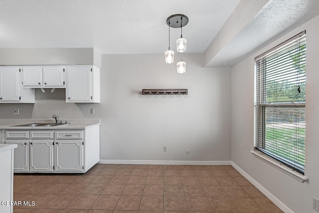1615 Opossum Cir, Horizon City, TX 79928 - kitchen with light countertops, white cabinets, hanging light fixtures, and tile patterned flooring