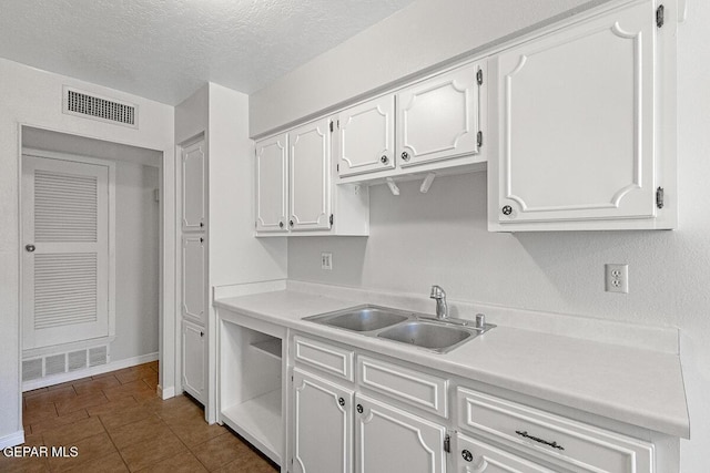 1615 Opossum Cir, Horizon City, TX 79928 - kitchen with white cabinets, light countertops, a textured ceiling, and dark tile patterned floors