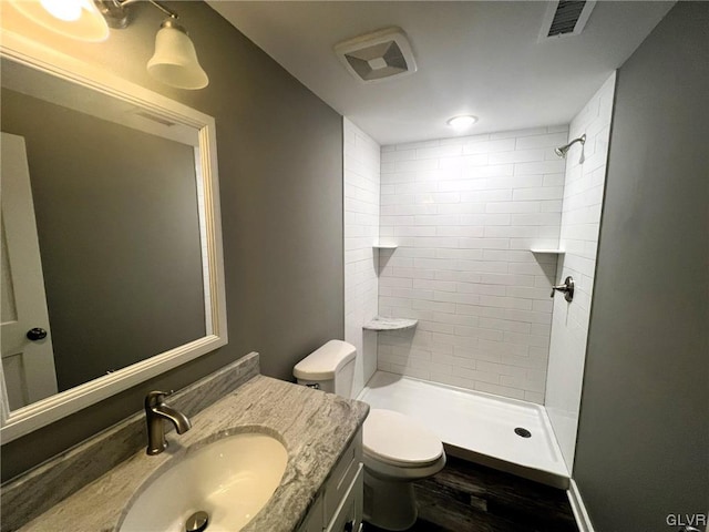 bathroom featuring tiled shower, vanity, and toilet