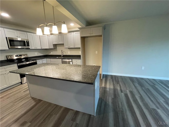 kitchen featuring white cabinets, dark hardwood / wood-style flooring, stainless steel appliances, and hanging light fixtures