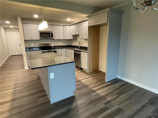 kitchen featuring a center island, sink, dark hardwood / wood-style floors, appliances with stainless steel finishes, and decorative light fixtures