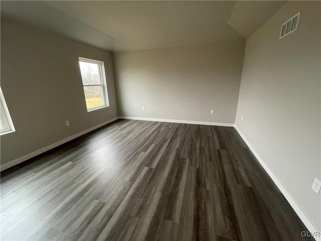 unfurnished room featuring dark hardwood / wood-style floors and vaulted ceiling