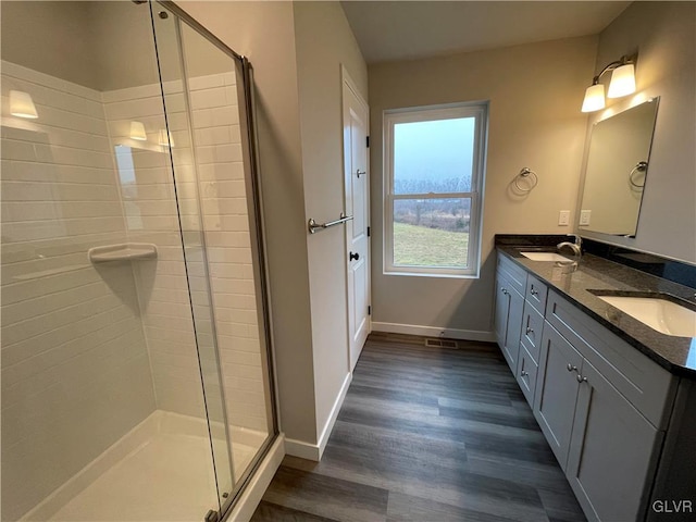 bathroom featuring wood-type flooring, vanity, and a shower with shower door