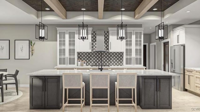 kitchen with beam ceiling, high quality fridge, a large island, and wall chimney exhaust hood