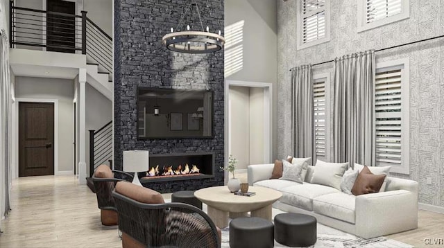 living room featuring a fireplace, a high ceiling, light wood-type flooring, and a notable chandelier