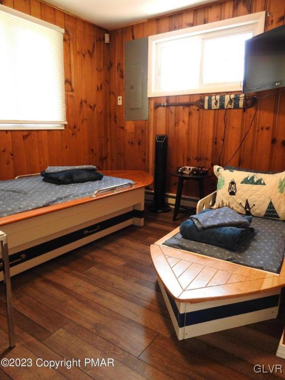 bedroom featuring wood walls, dark hardwood / wood-style floors, and electric panel