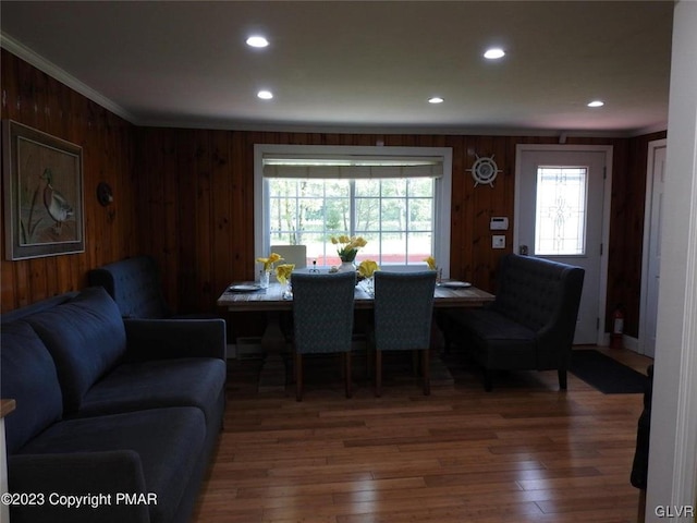 dining area featuring ornamental molding, wood walls, and dark wood-type flooring