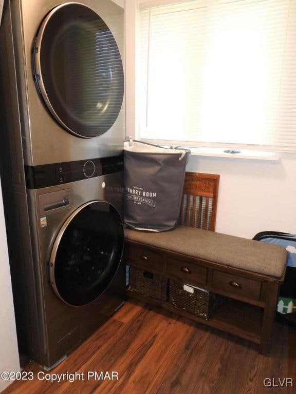 washroom with stacked washer and dryer and dark hardwood / wood-style flooring