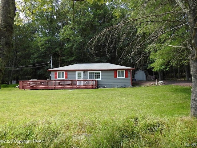 view of front of property with a front yard, a wooden deck, and a shed