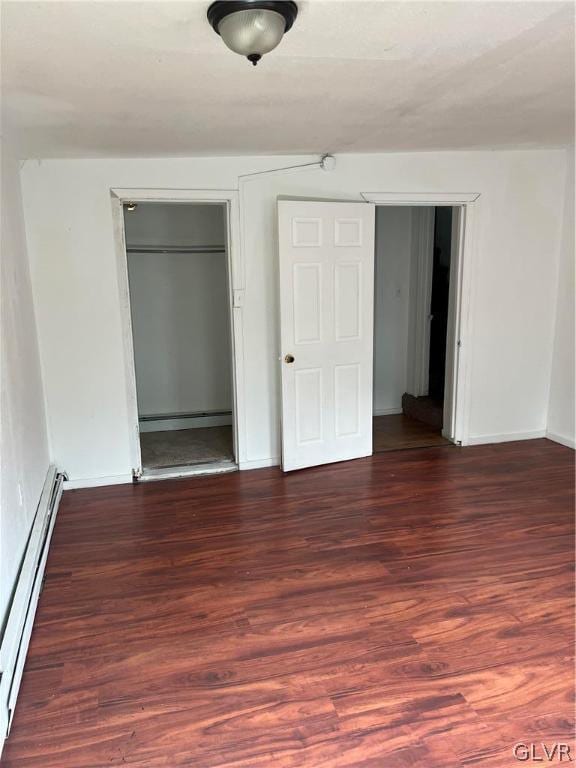 unfurnished bedroom with a baseboard heating unit and hardwood / wood-style flooring