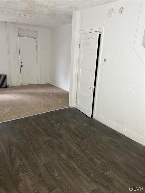 empty room featuring radiator and dark carpet