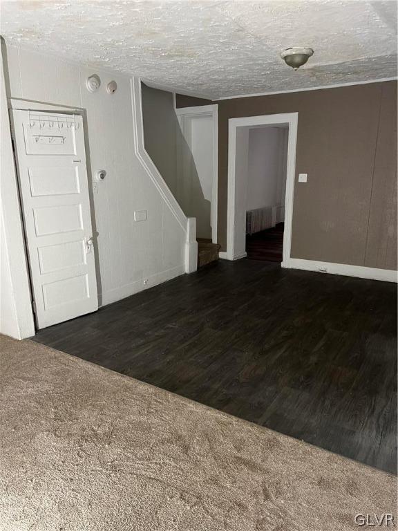 unfurnished room with a textured ceiling and dark hardwood / wood-style floors