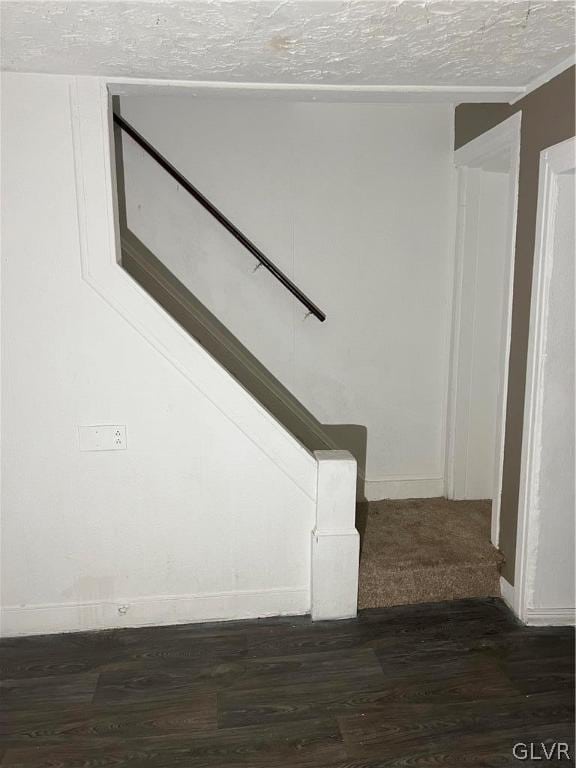 staircase featuring a textured ceiling and hardwood / wood-style flooring