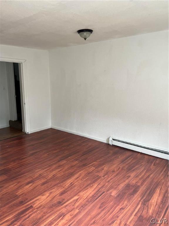 empty room with wood-type flooring and a baseboard radiator